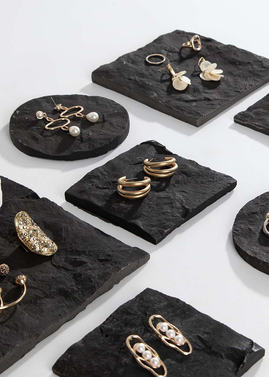 Various jewelry displayed on black stone slabs.