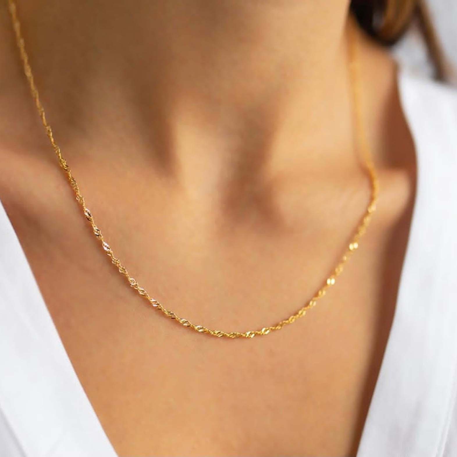 A close up of a gold chain on a woman's neck.