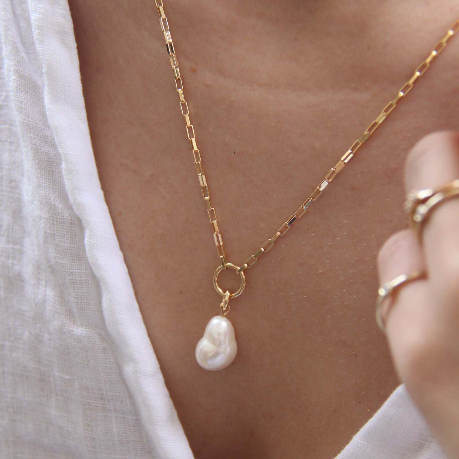 A close up of a pearl necklace on a woman's neck.