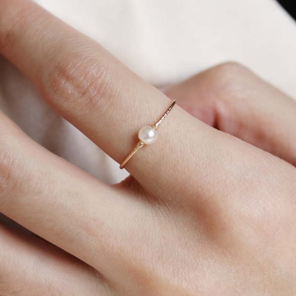A close up of a pearl ring on a woman's finger.