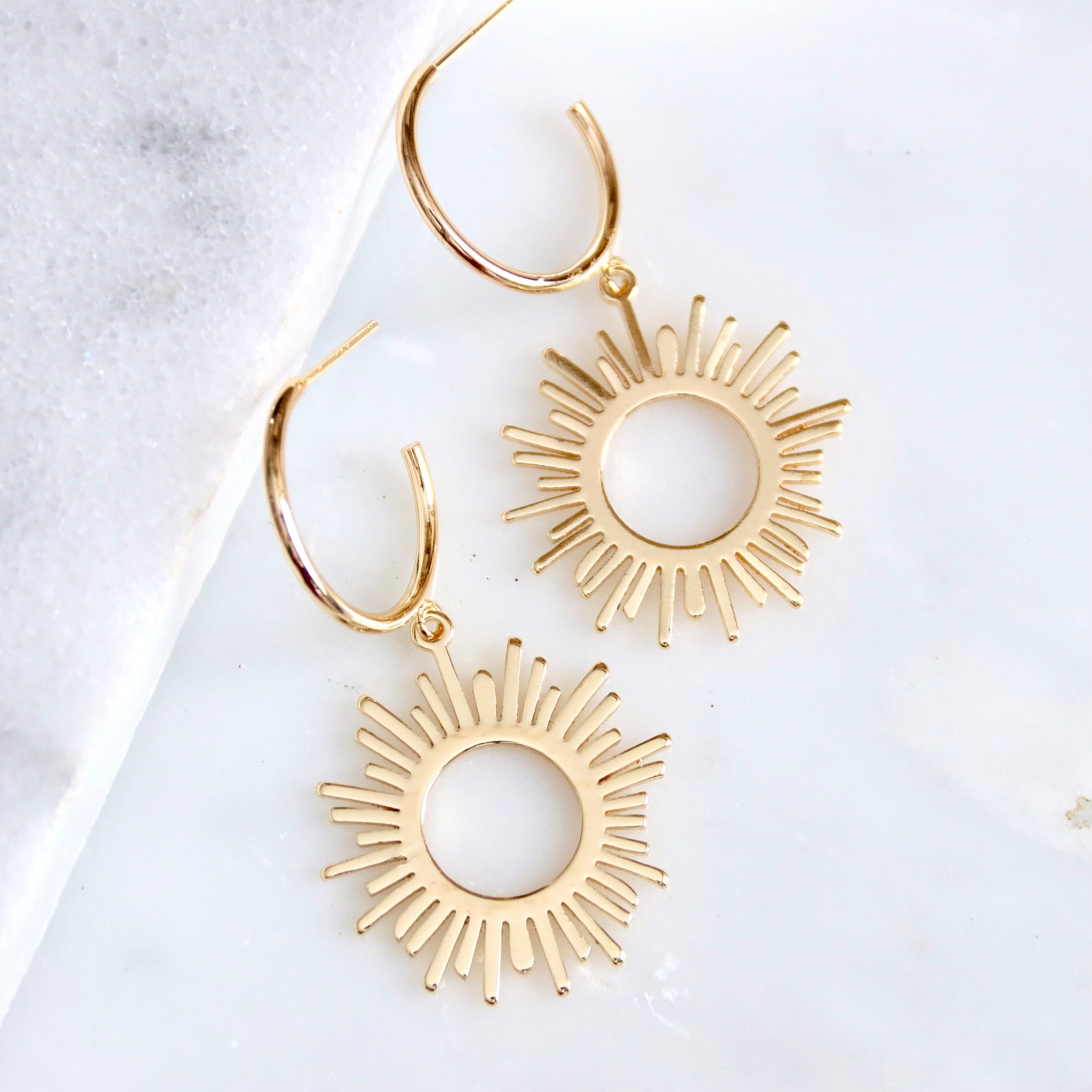 A close up of sun earrings on a table.