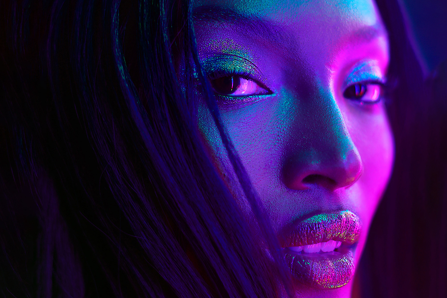 A close-up portrait of a woman with blue and pink lighting.