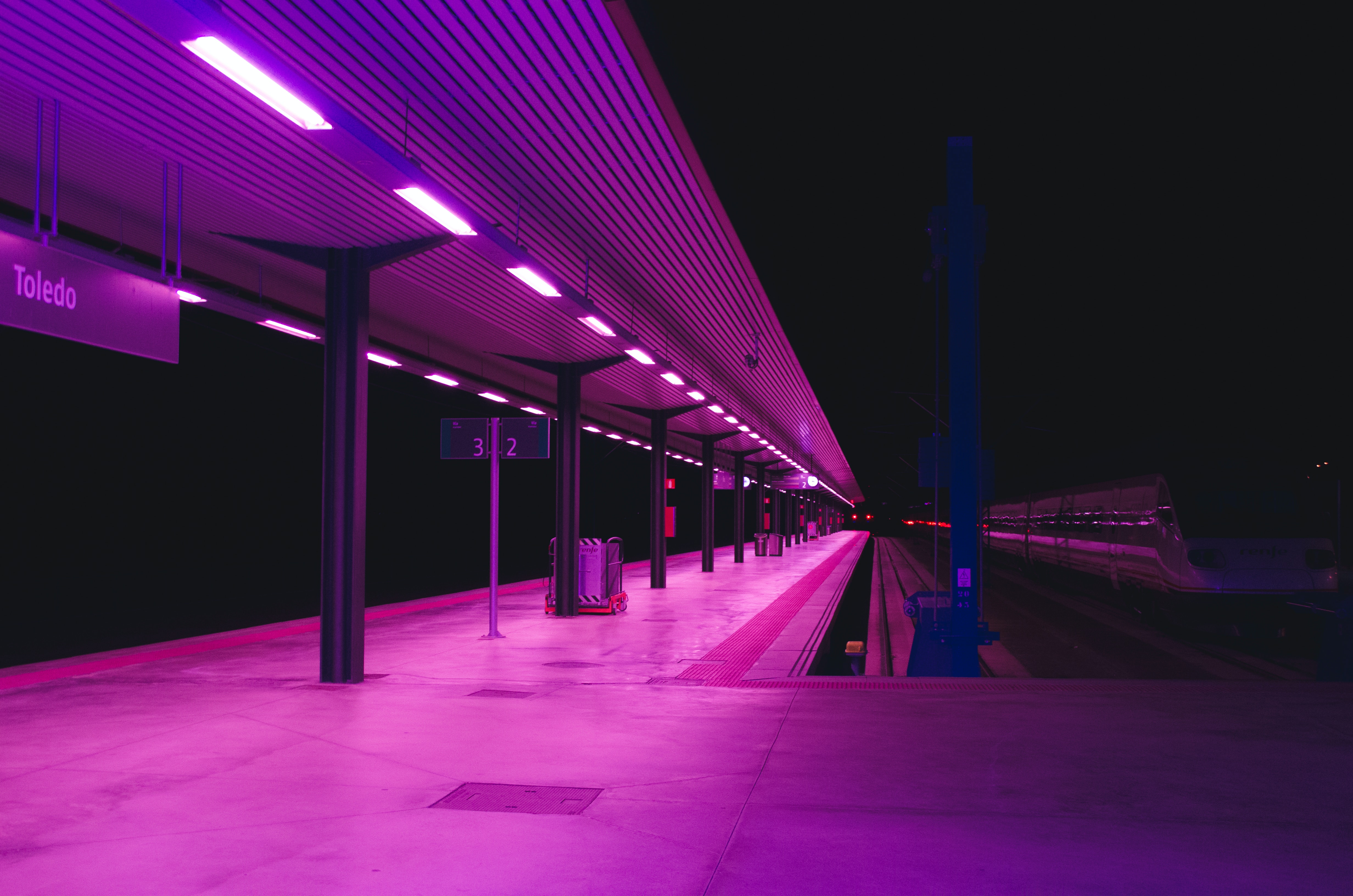An empty train station at night lit up in pink.